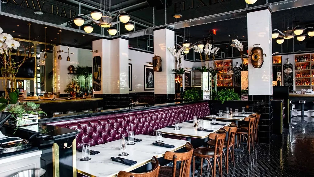 Upscale restaurant with purple booth, marble tables, and bar.