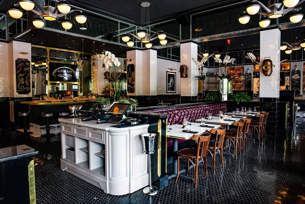 Upscale restaurant interior with burgundy banquettes, bar, and POS systems.