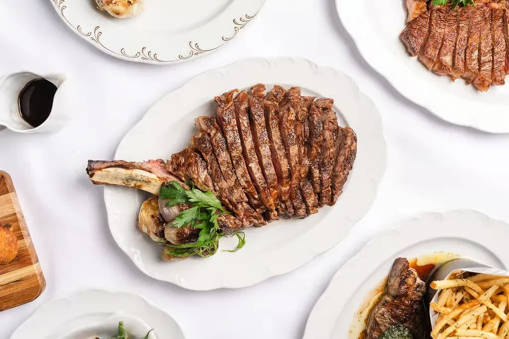 Overhead view of several plates of sliced steak and sides.
