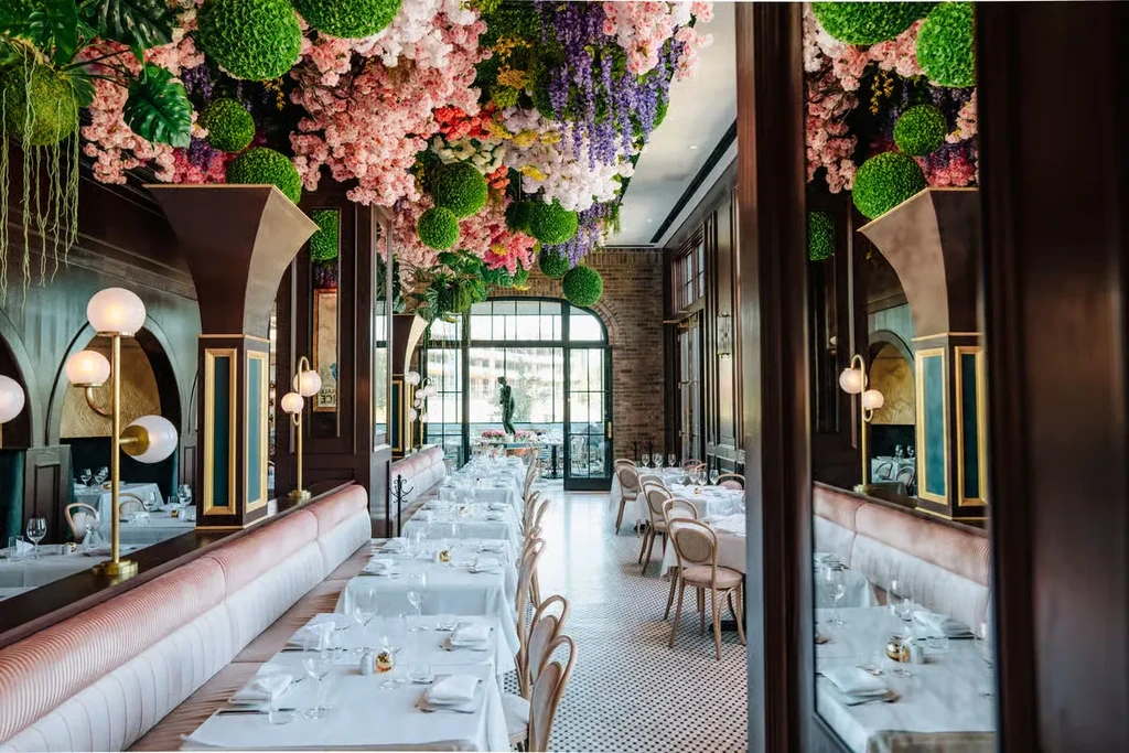 Restaurant interior with vibrant floral and greenery ceiling installation.