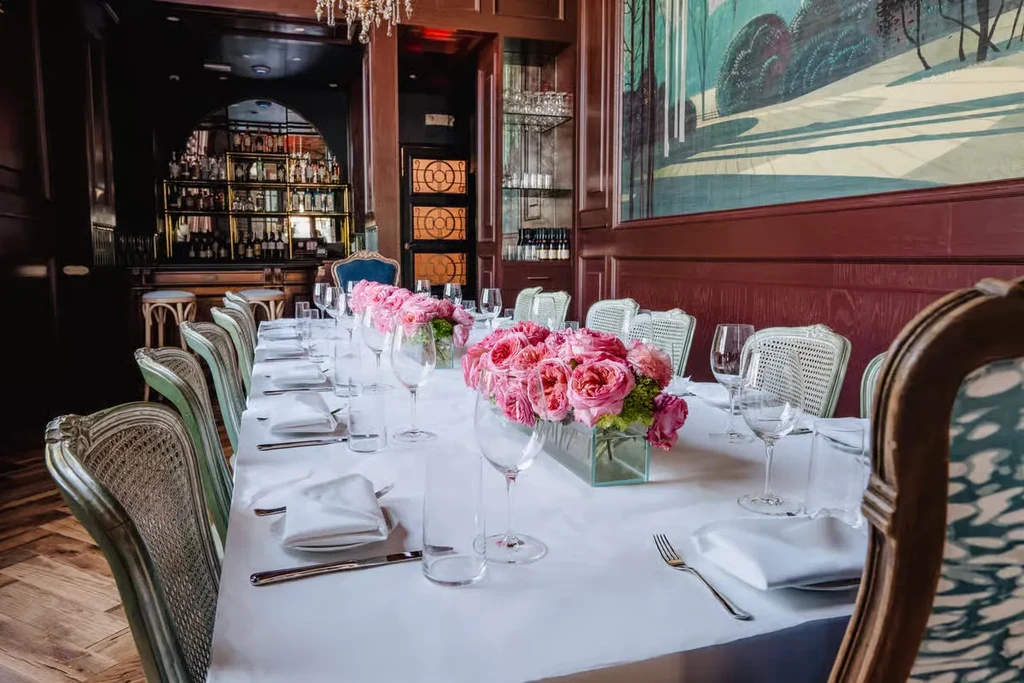 Elegantly set dining table with pink roses and an abstract mural.