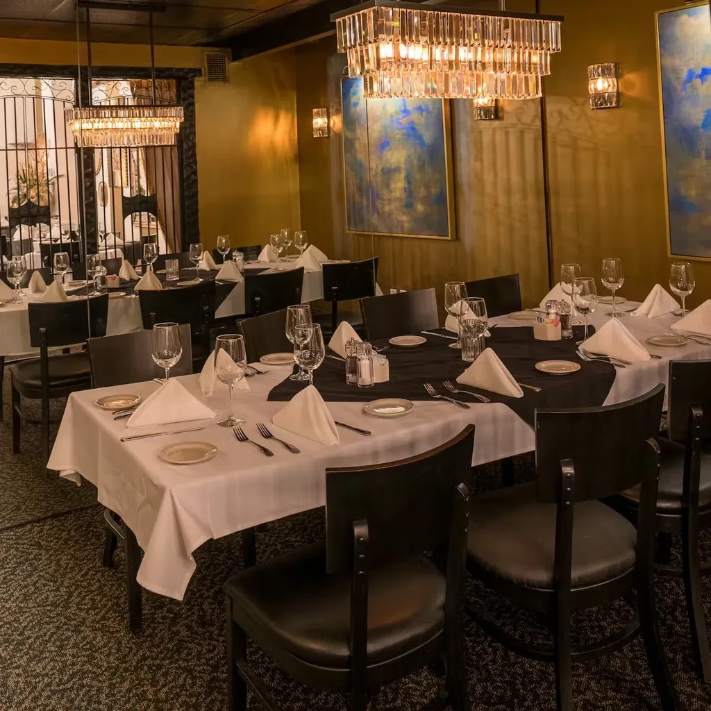 Elegant dining room with tables set for guests, crystal chandeliers.