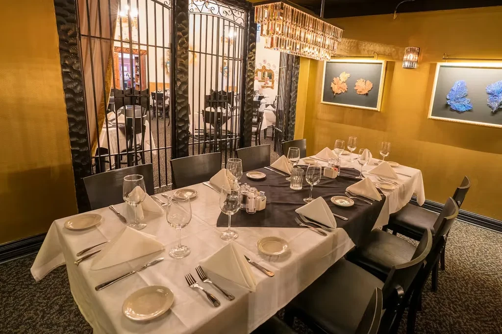 Restaurant dining table set with plates, silverware, and wine glasses.