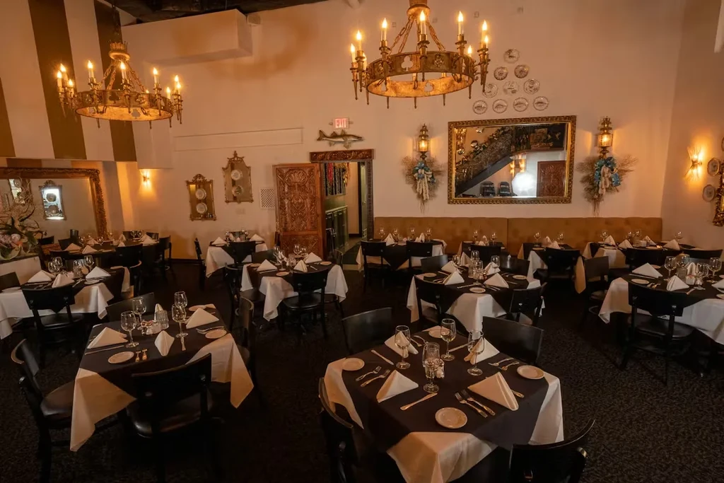 Formal restaurant dining room with multiple set tables and elegant decor.