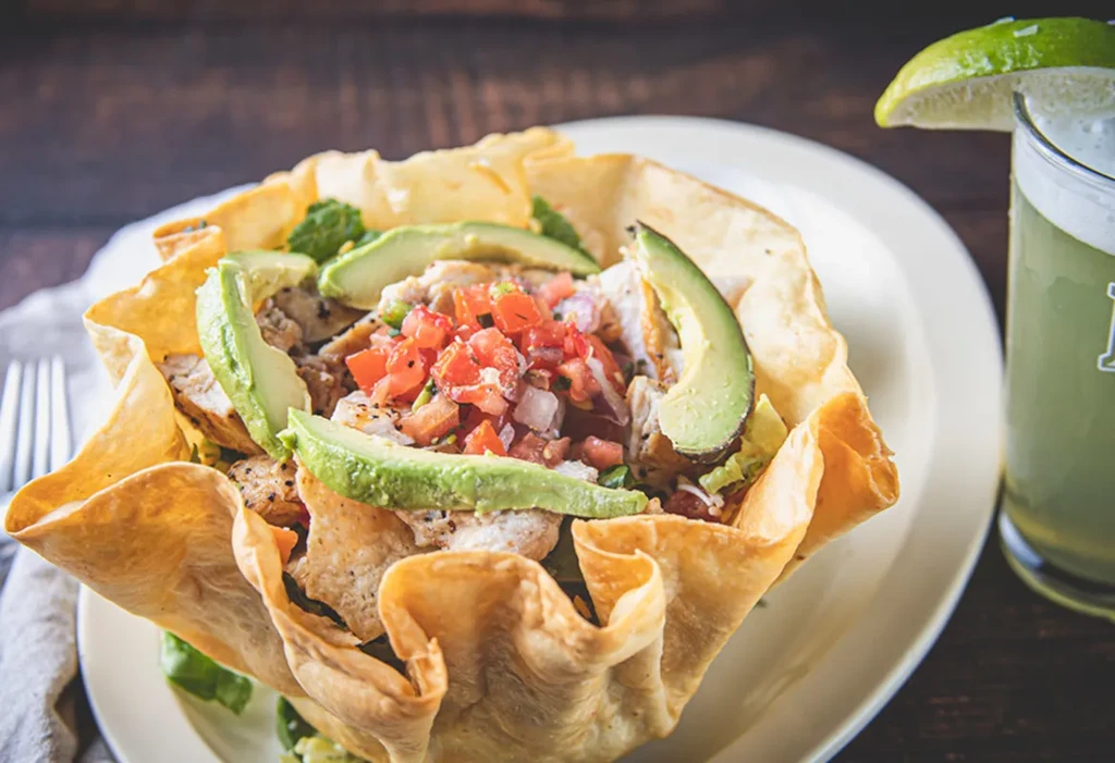 Close-up of a taco salad in a fried tortilla bowl with chicken.
