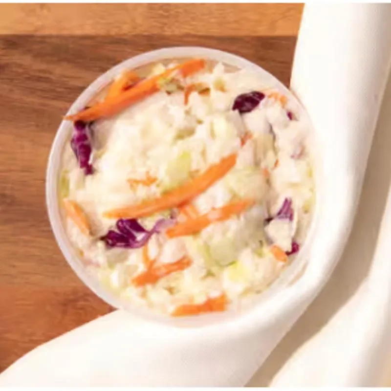 Close-up, top-down view of coleslaw in a clear plastic container.
