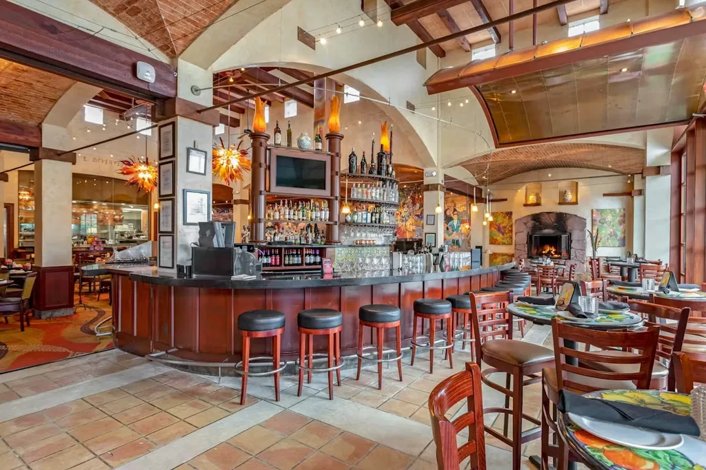 Restaurant interior with a large bar, dining area, and open kitchen.
