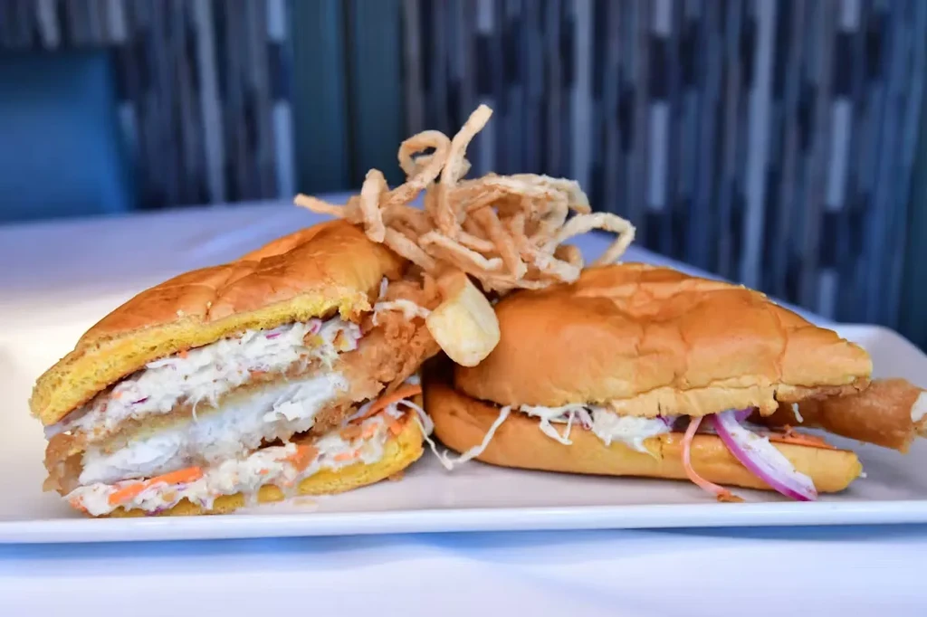 Two golden-brown fish sandwiches with coleslaw and crispy fried onions.