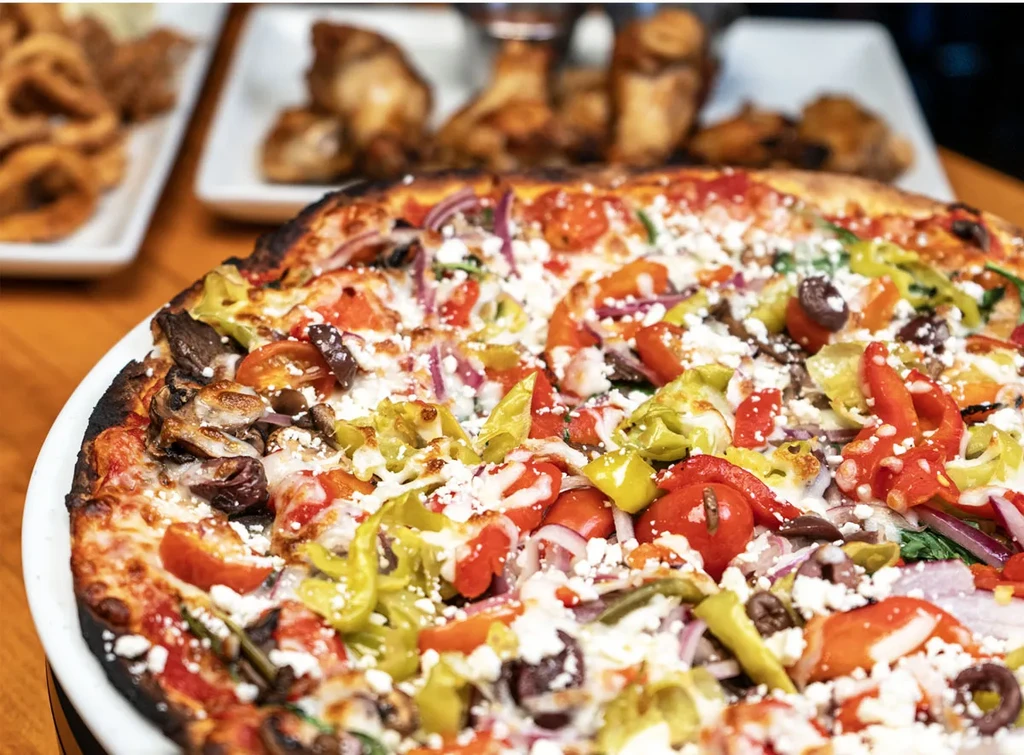 Close-up of a colorful pizza with various toppings on a white plate.
