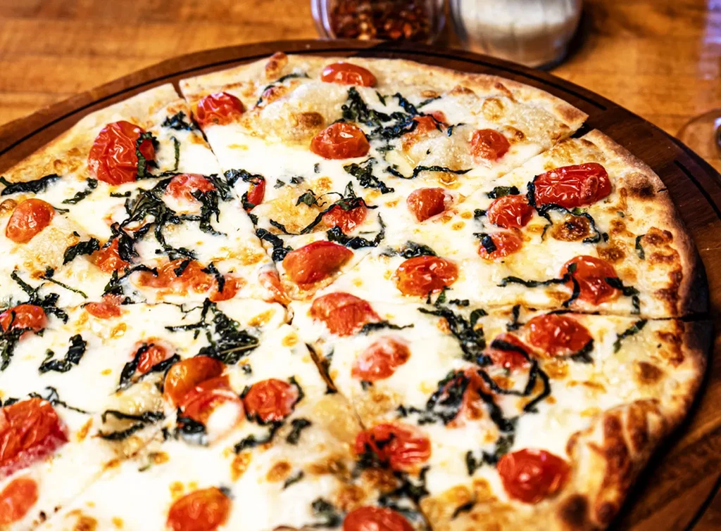 Close-up, high-angle shot of a freshly baked pizza with tomatoes and basil.