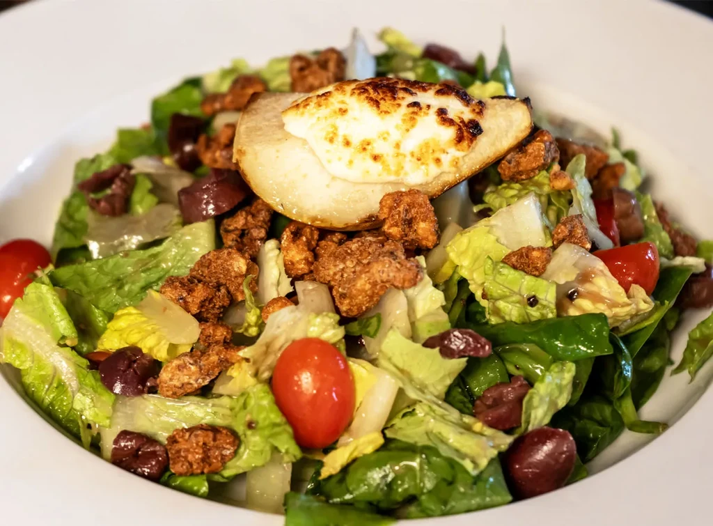 Vibrant salad with roasted pear, cheese, cherry tomatoes, and olives.