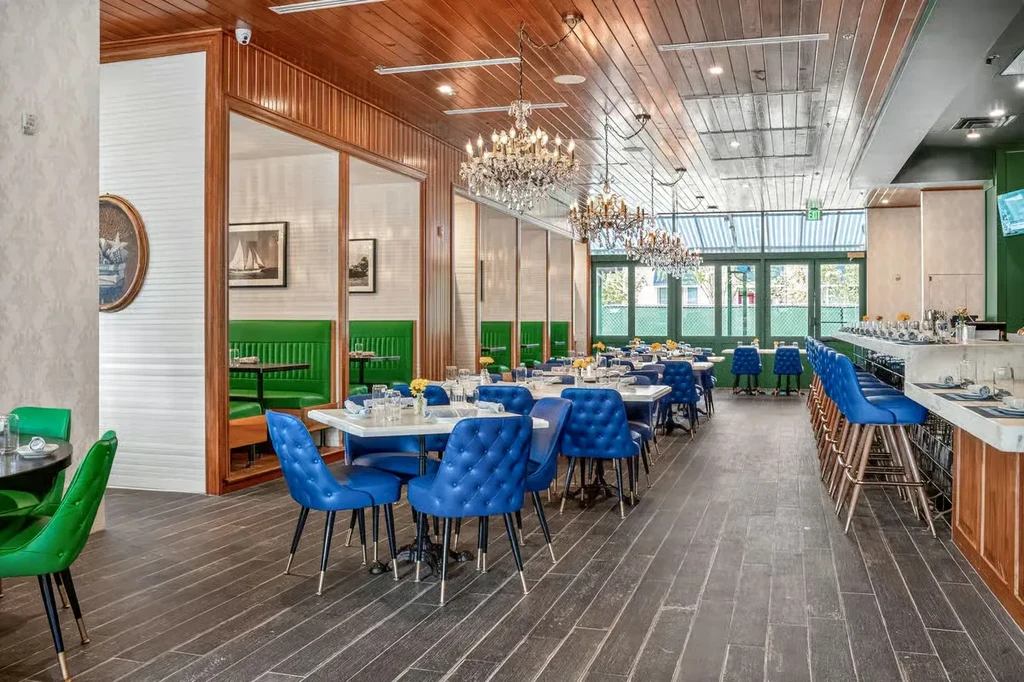 Restaurant interior with blue chairs, white tables, and crystal chandeliers.