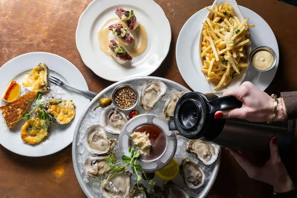 Table with oysters, fries, nigiri, and baked oysters.