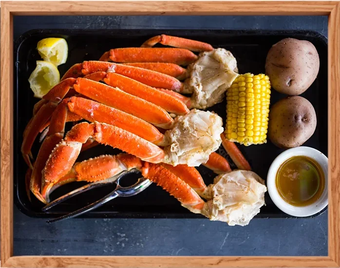 Top-down view of a seafood boil with crab legs and sides.