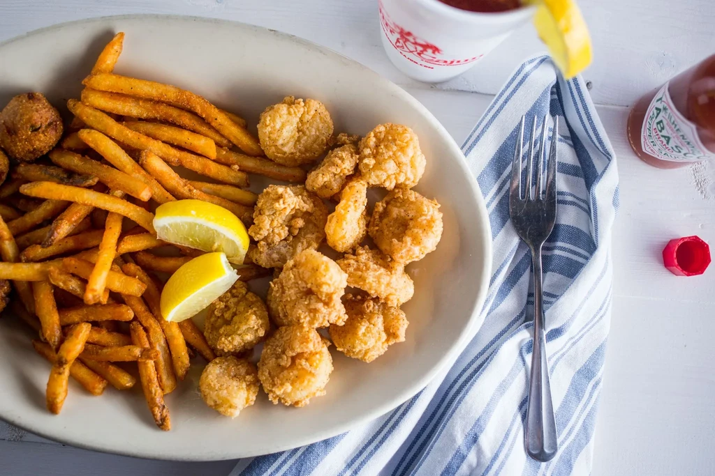 Fried seafood and french fries with lemon wedges on a plate.