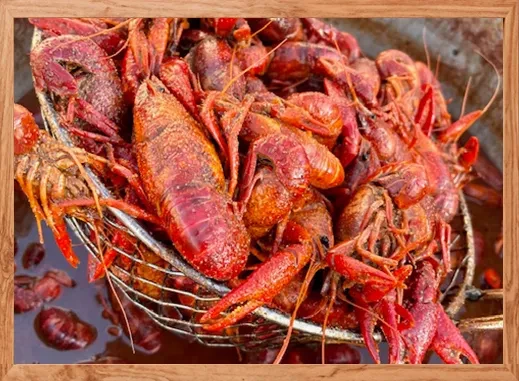 Cooked reddish-orange crawfish in a metal mesh skimmer.
