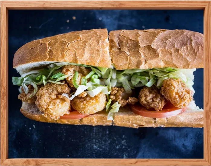 Close-up of a shrimp po'boy sandwich with lettuce and tomato.