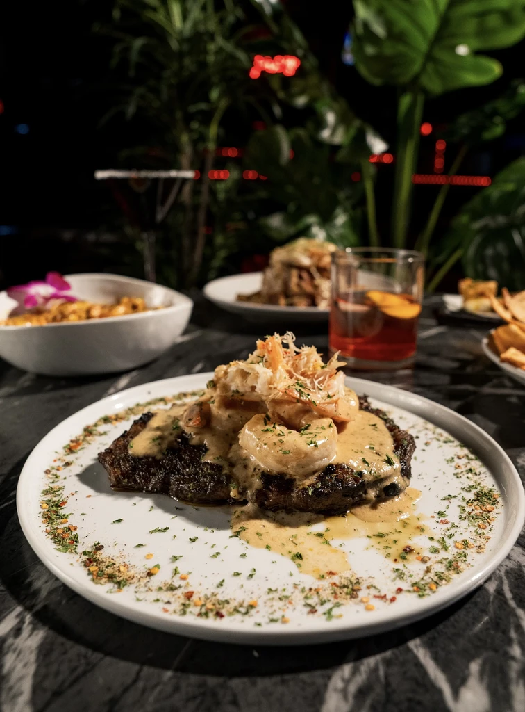 Steak and seafood dish with creamy sauce, herbs, and pepper flakes.