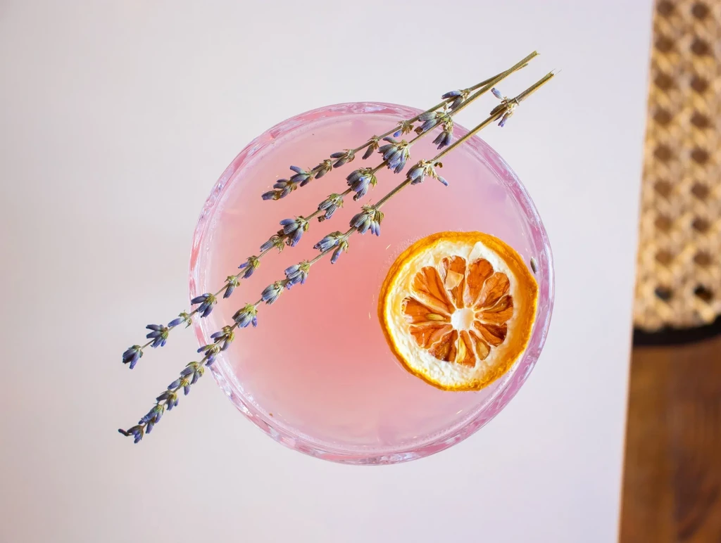Light pink cocktail garnished with lavender and a dried orange slice.