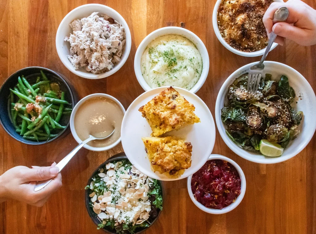 Overhead view of a wooden table with eight bowls of various foods.