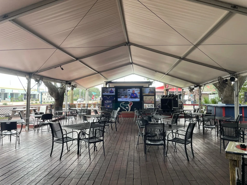 Outdoor patio bar with tables, chairs, and multiple TVs.