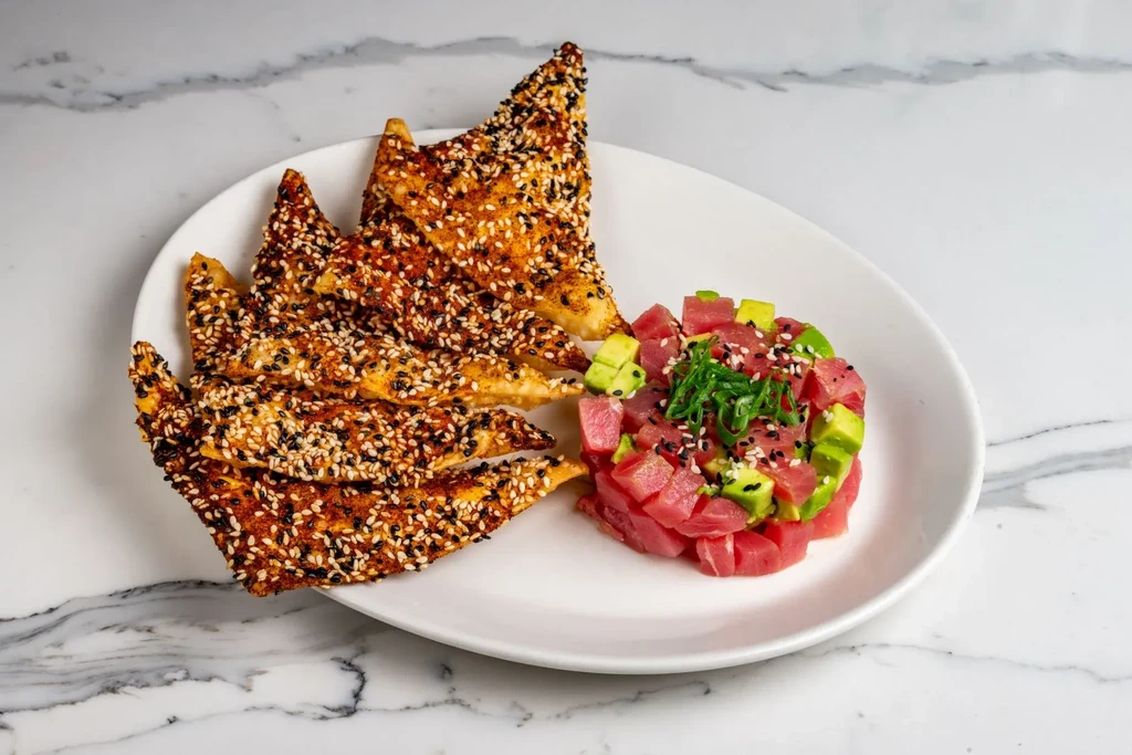 Tuna poke or tartare with avocado, sesame crackers, and spices.