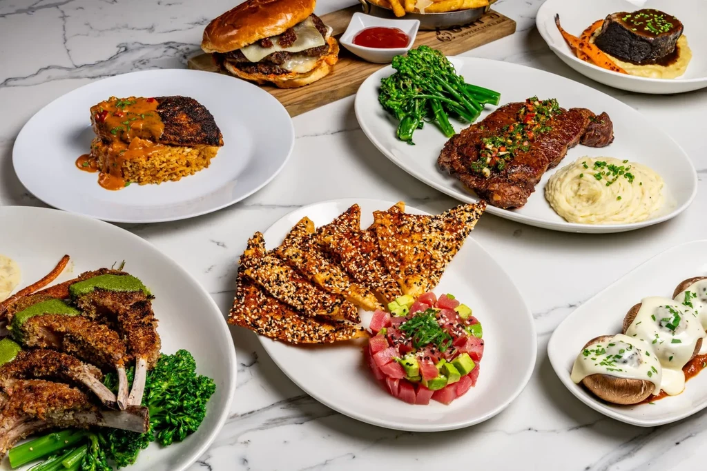 High-angle view of multiple restaurant dishes on a white marble table.