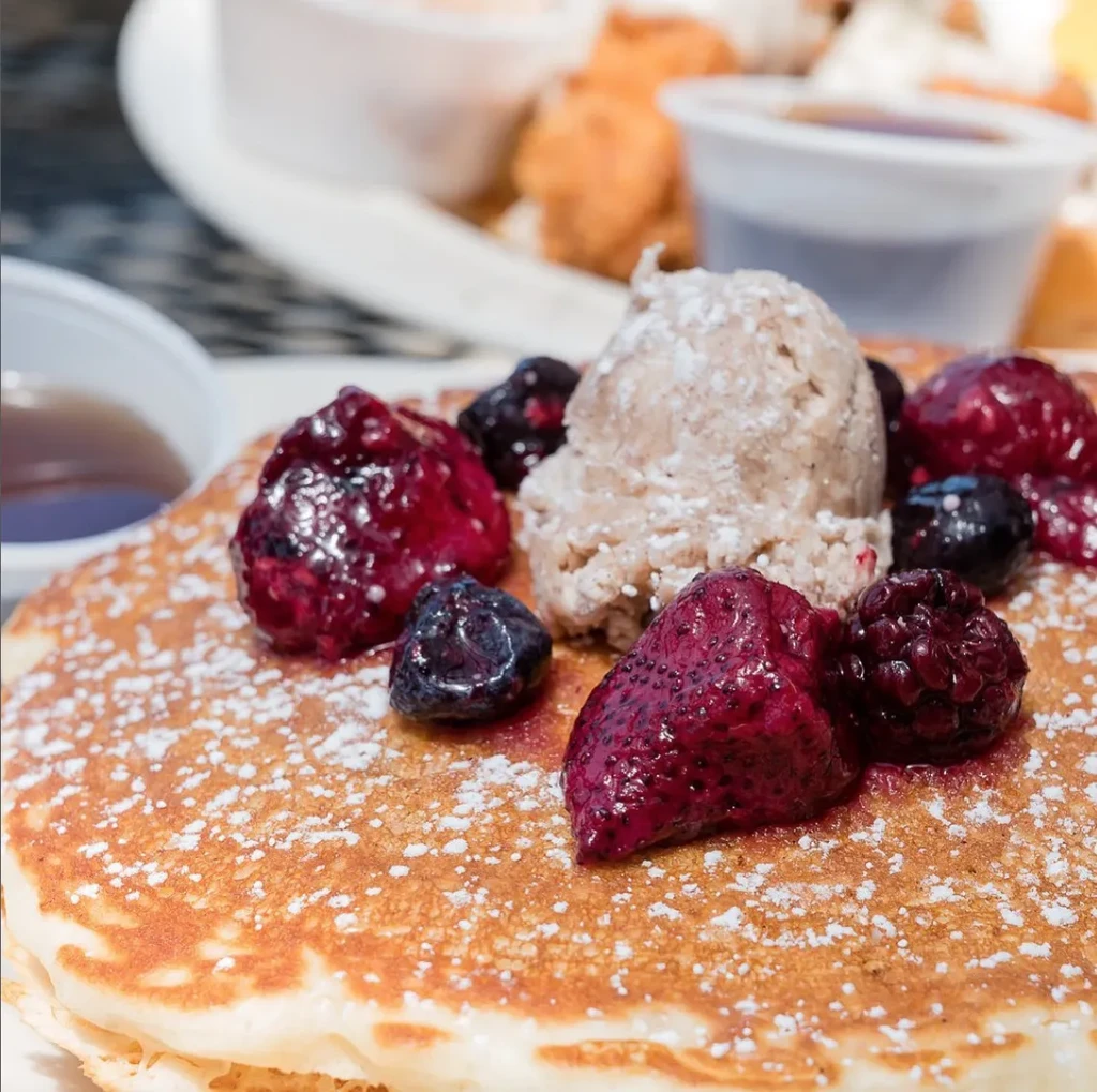 Pancakes with ice cream, berries, and powdered sugar.