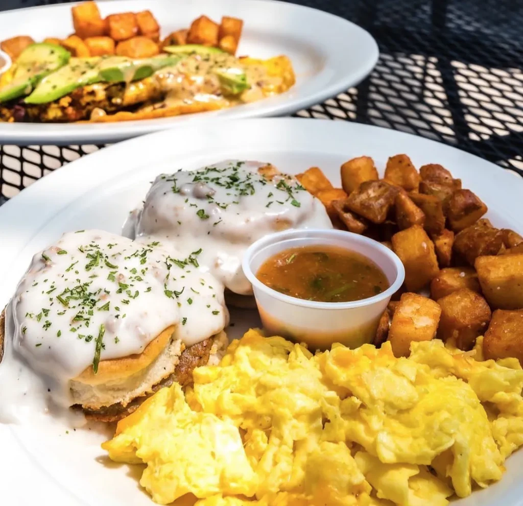 Two plates of breakfast food with eggs, biscuits, and potatoes.