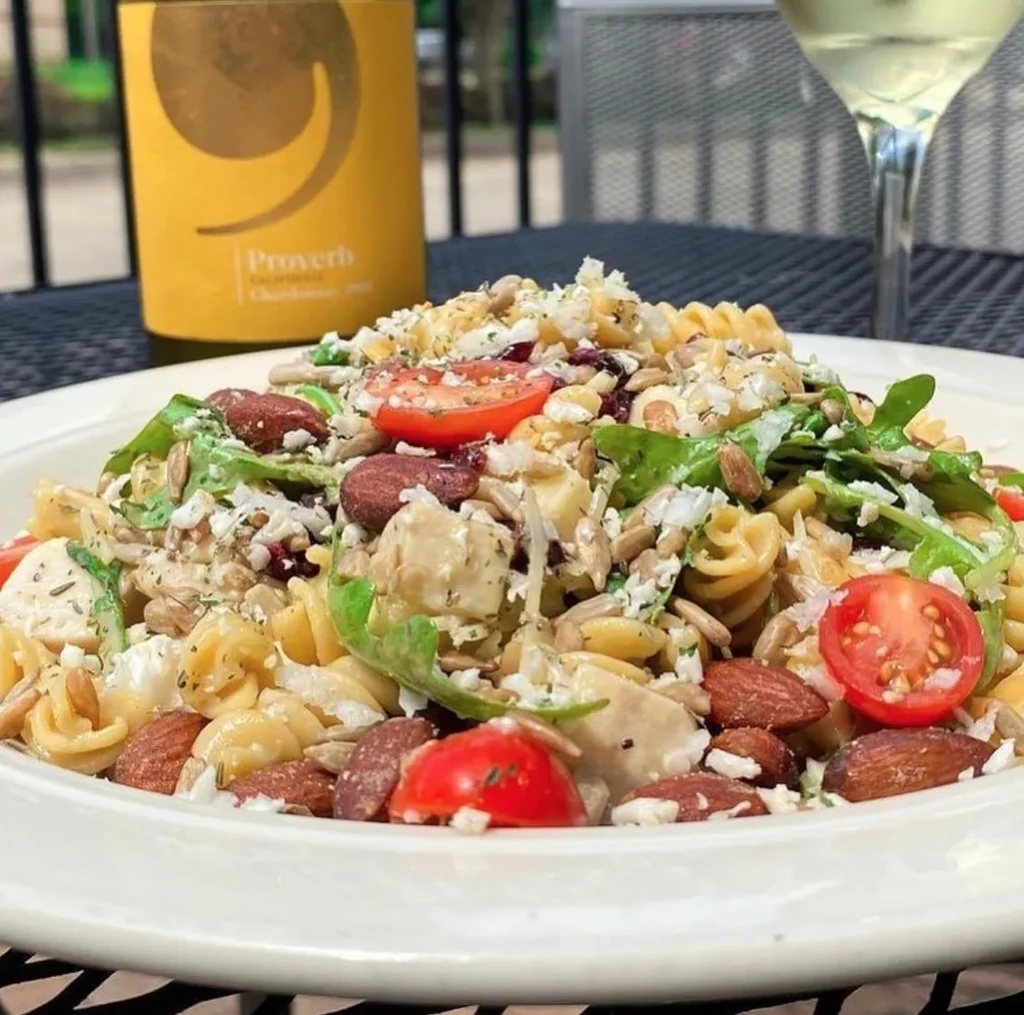 Close-up of pasta salad with tomatoes, nuts, seeds, and cheese.