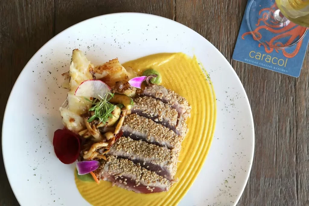 Seared tuna with sauce, potatoes, mushrooms, radishes, and microgreens.
