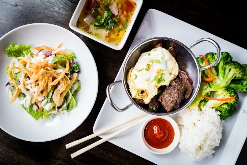 Top-down view of various Asian dishes on a dark table.