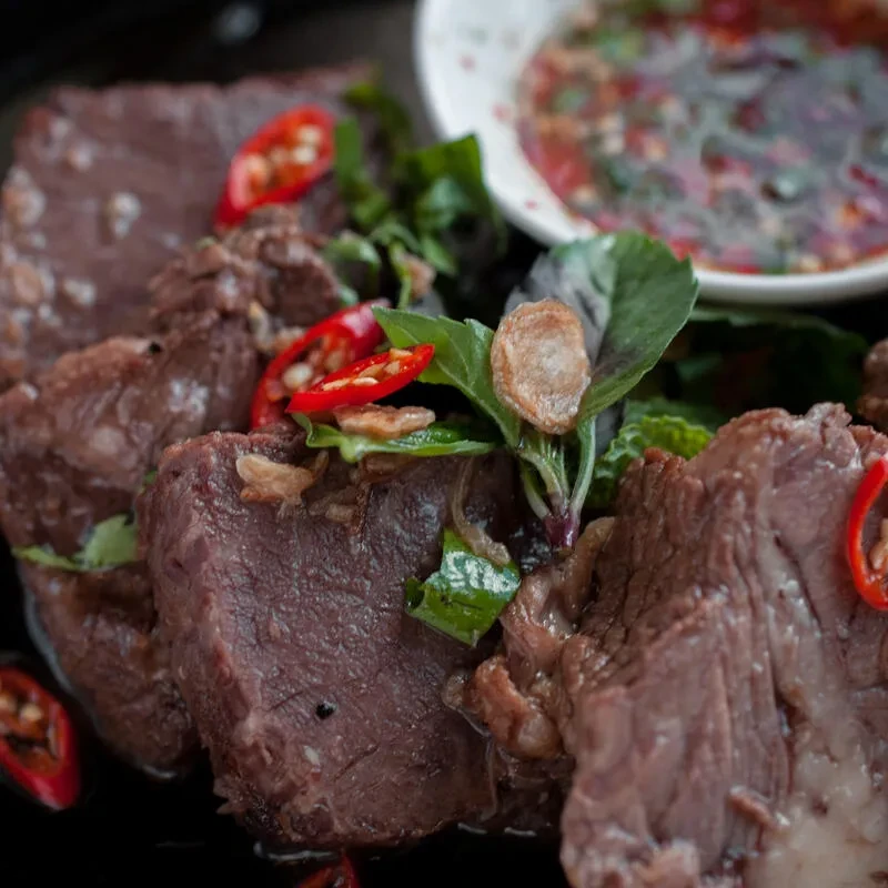 Braised beef chunks garnished with herbs, chili, and fried garlic.