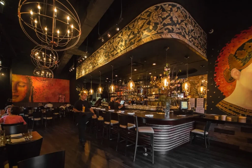 Dimly lit bar area with staff and patrons in a stylish restaurant.