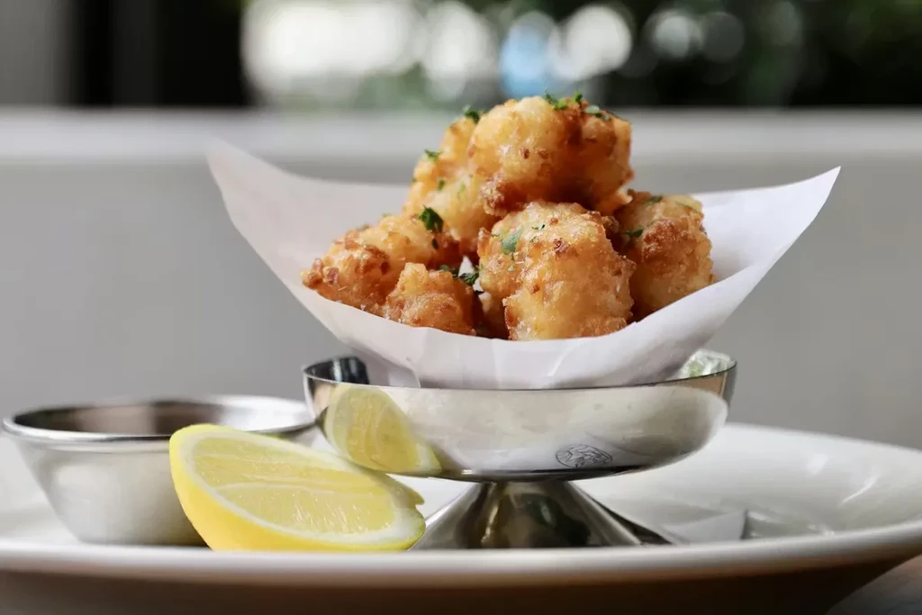 Fried fritters or seafood with lemon wedges and herbs.