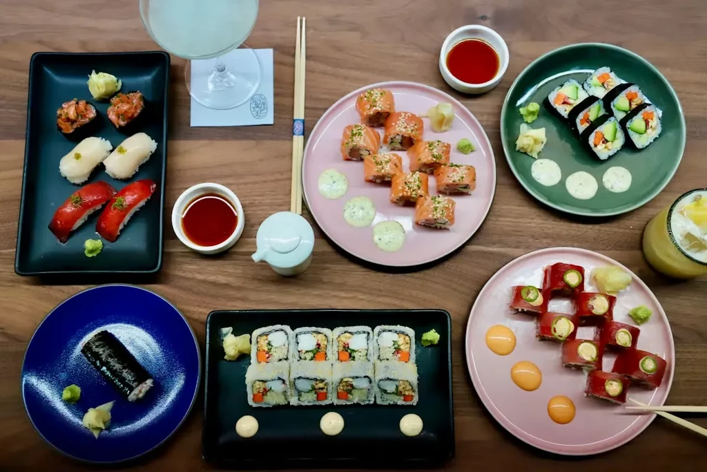 Overhead view of various sushi rolls and nigiri on a wooden table.