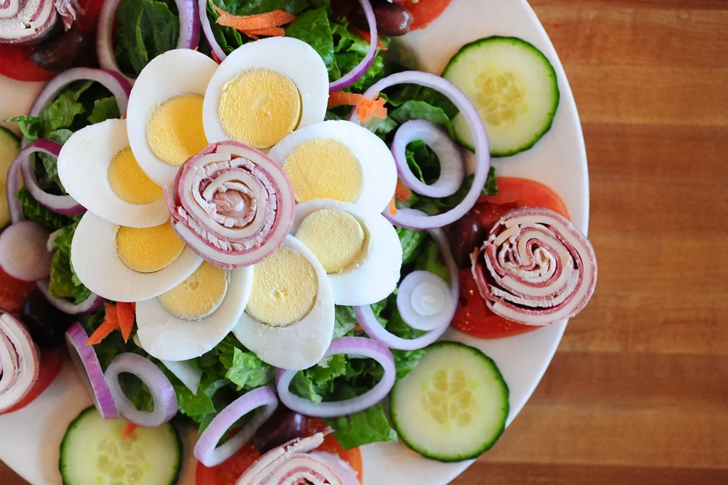 Top-down view of a vibrant salad with eggs, meat, and vegetables.