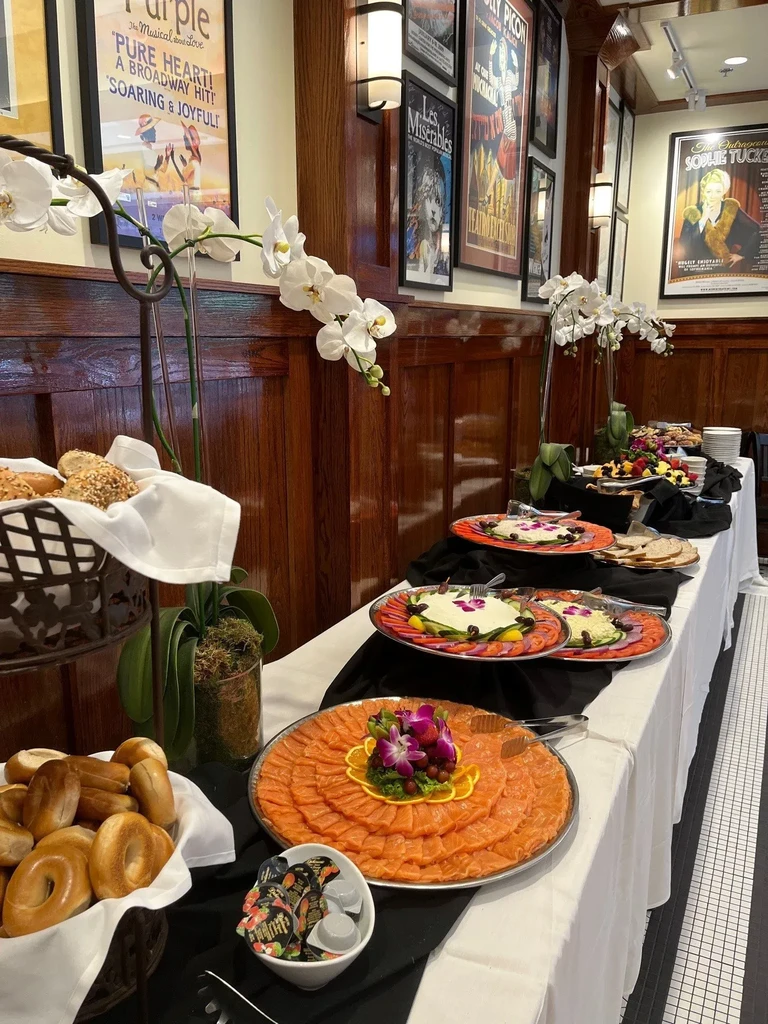 Buffet table with smoked salmon, bread, pastries, fruits, and cream cheese.