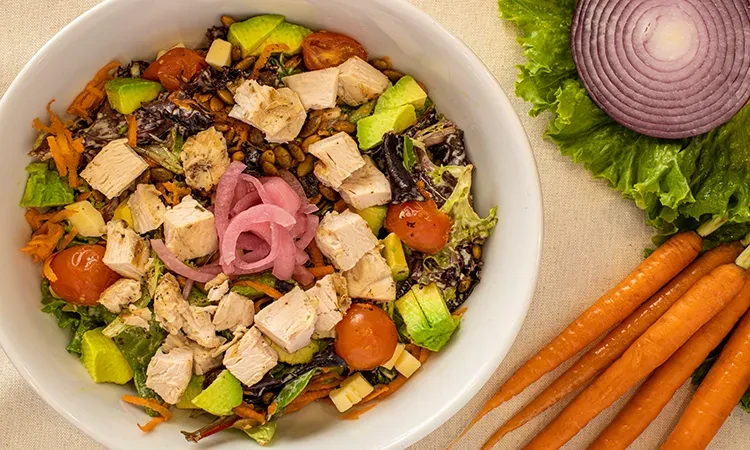 Vibrant salad with chicken, avocado, pickled onions, and mixed greens.