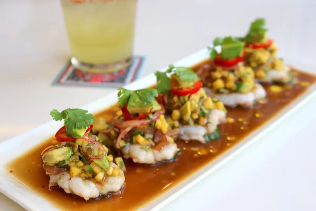 Shrimp ceviche appetizers with avocado and chili on a white plate.