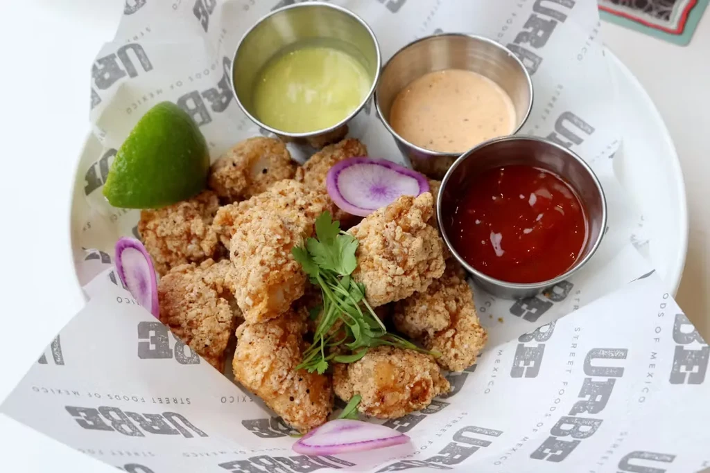 Fried food with lime, herbs, and three dipping sauces.