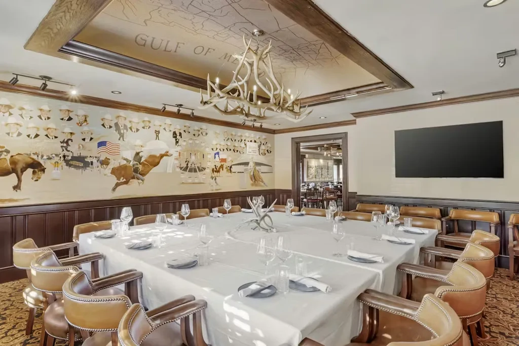 Restaurant dining room with antler chandelier and Western-themed mural.