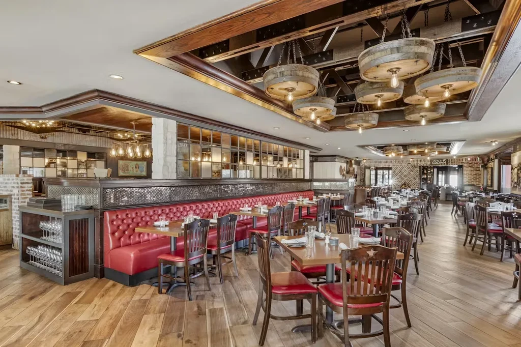 Interior of a spacious restaurant with rustic wooden decor and red seating.