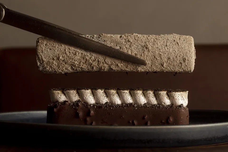 Dessert with a chocolate base, meringue, and a lifted cake piece.
