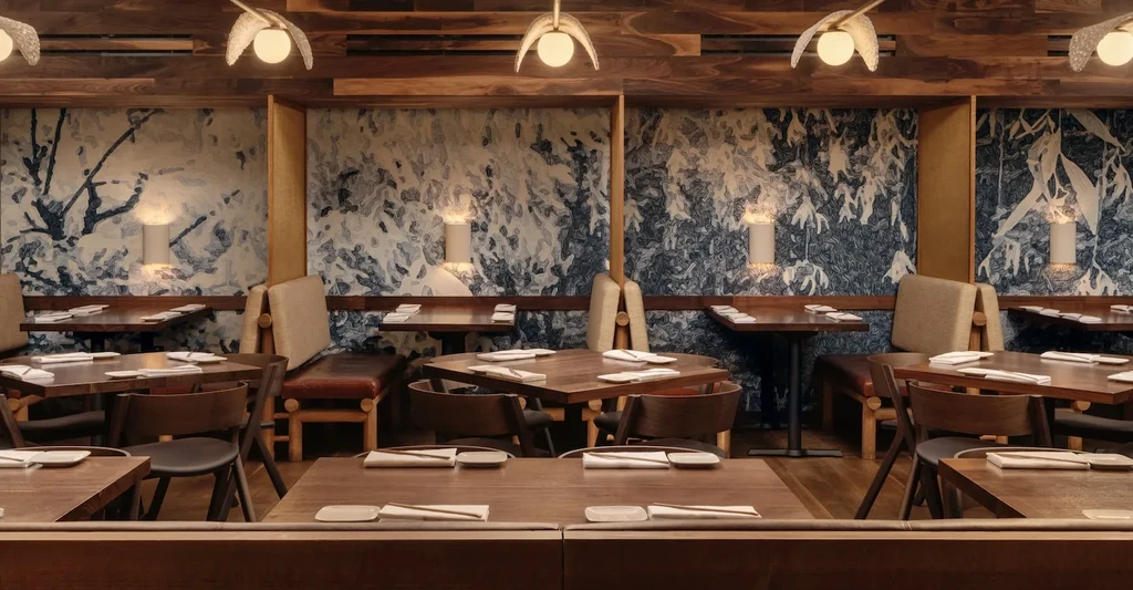 Restaurant interior with wooden tables, chairs, and patterned wallpaper.