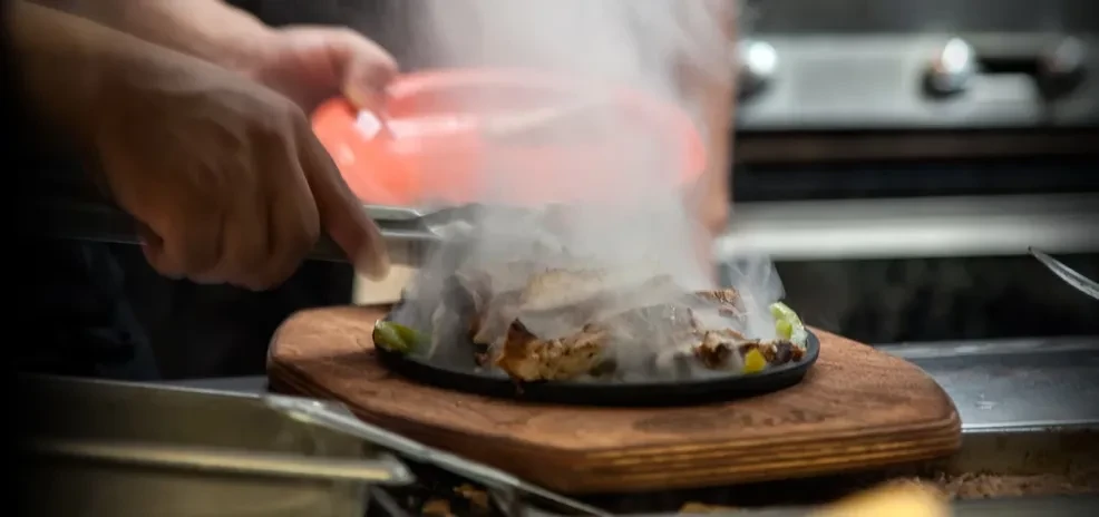 Sizzling fajita meat and lime in a cast iron skillet.