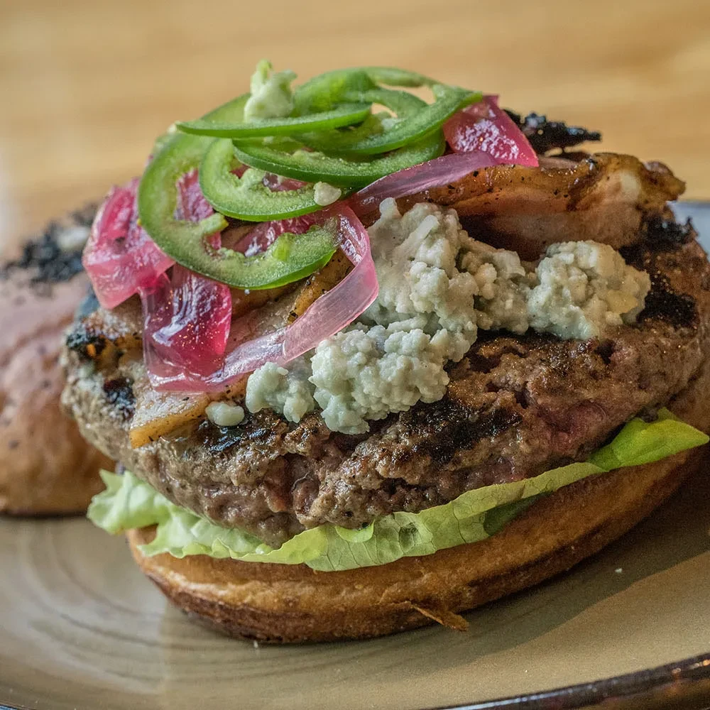 Gourmet burger with grilled beef, blue cheese, jalapeños, and red onions.