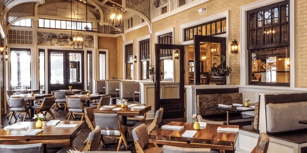 Elegant restaurant dining area with tables, booths, plants, and festive decor.