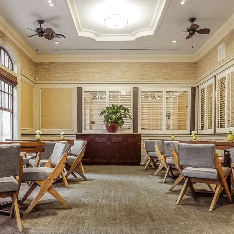 Elegant room with X-base chairs, wood credenza, and plantation shutters.