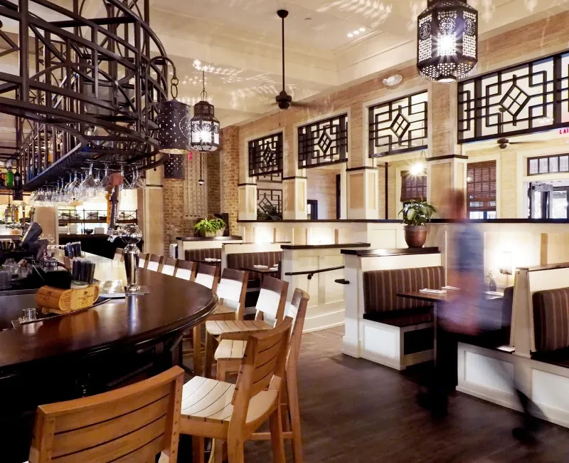 Rustic-elegant restaurant with dark wood bar, booth seating, and exposed brick.